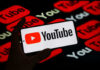 Hand holding phone showing YouTube logo.