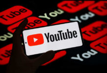 Hand holding phone showing YouTube logo.