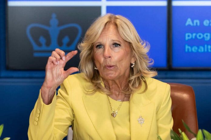 A woman in a yellow blazer speaking passionately during a meeting