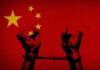 Two hands in handcuffs against a red background with stars