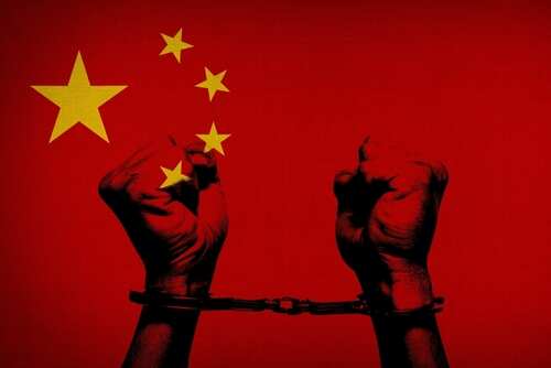 shutterstock_2033632514.jpg Two hands in handcuffs against a red background with stars