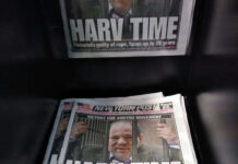 Newspapers on rack with headline about trial verdict