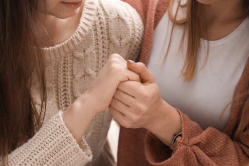 shutterstock_1324641800.jpg Two people holding hands in a supportive gesture