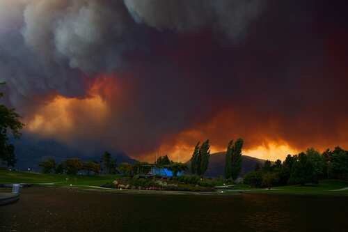 Dramatic sky filled with smoke and fire colors over a lake