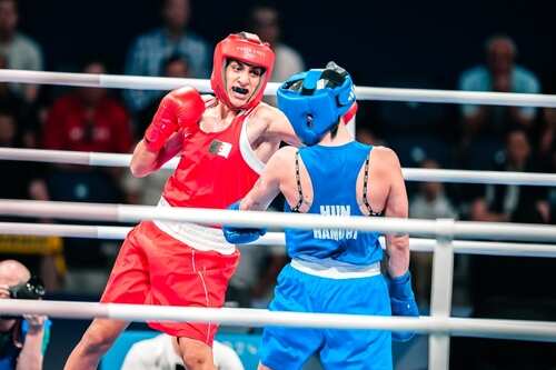 Two boxers in a ring, one in red and the other in blue, engaged in a match
