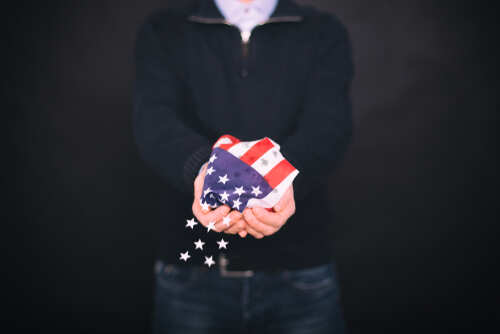 Person holding a crumpled American flag with stars falling from it