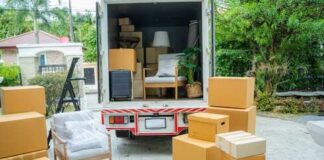 A moving truck with furniture and boxes parked outside a house