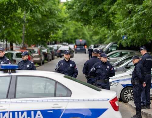 shutterstock_2307206295.jpg Group of police officers gathered on a street near parked cars