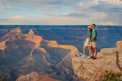 shutterstock_2337120063.jpg A couple standing on the edge of the Grand Canyon during sunset