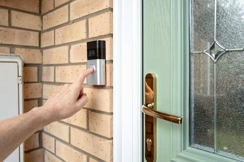 shutterstock_2479983779.jpg A hand pressing a doorbell button on a brick wall