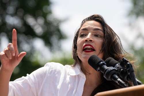 A woman passionately speaking at a podium with microphones