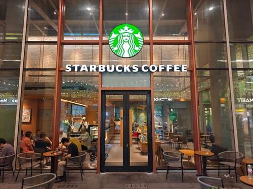 Exterior view of a Starbucks coffee shop with customers seated outside
