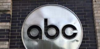 Metal logo of 'abc' mounted on a brick wall