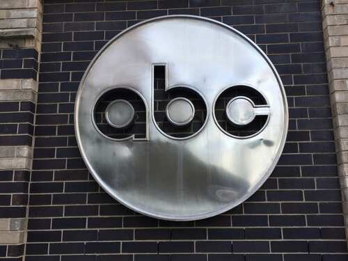 Metal logo of 'abc' mounted on a brick wall