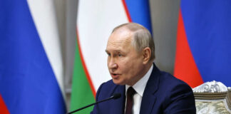 Man speaking at conference with flags in background