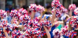 Group of young cheerleaders waving pom-poms in a parade