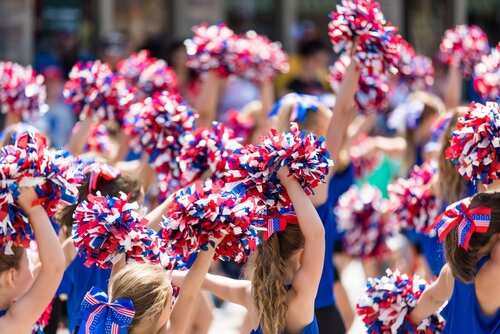 shutterstock_2213545919.jpg Group of young cheerleaders waving pom-poms in a parade