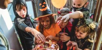 Children in Halloween costumes eagerly reaching for candy from a bowl