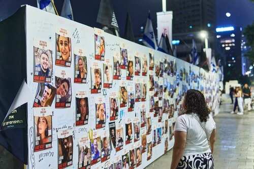 A woman observing a memorial wall filled with photographs and messages