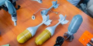 Various drone components and model rocket parts displayed on a wooden surface