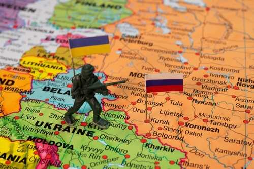 shutterstock_2512205783.jpg A toy soldier positioned on a map between Ukraine and Russia with flags