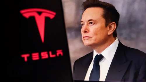 shutterstock_2632037249.jpg Close-up of a man in a suit next to a Tesla logo