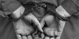 Close-up of hands in handcuffs behind the back