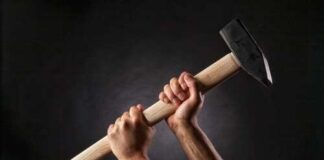 Hands gripping a large hammer against a dark background