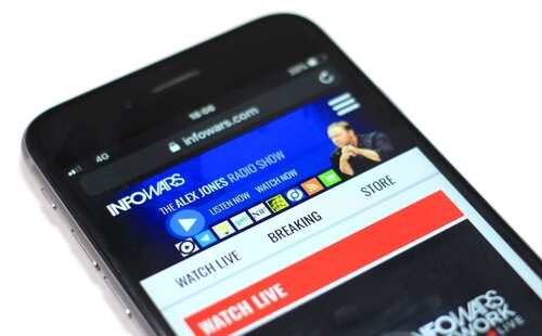 shutterstock_2429918485.jpg Mobile phone displaying the Infowars website interface