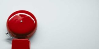 A red vintage alarm bell on a white surface