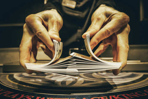 shutterstock_1597931185.jpg Casino dealer shuffling a deck of playing cards