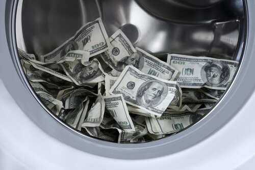 A washing machine drum filled with crumpled hundred dollar bills