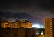 Nighttime view of urban buildings under a cloudy sky with distant lights