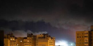 Nighttime view of urban buildings under a cloudy sky with distant lights