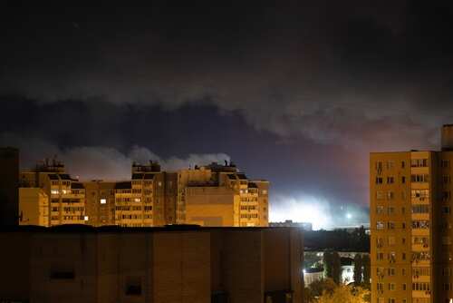 Nighttime view of urban buildings under a cloudy sky with distant lights