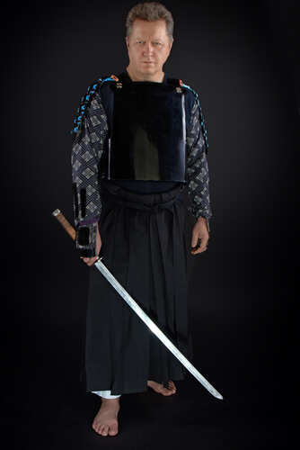 shutterstock_1782020117.jpg Man dressed in traditional samurai armor holding a katana