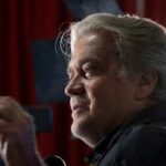 Bannon’s Call to Halt Foreign Visas — National Security Alert Man with gray hair speaking at an indoor event with dramatic lighting