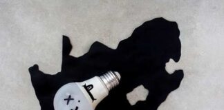 A light bulb with a face illustration placed on a black silhouette of South Africa