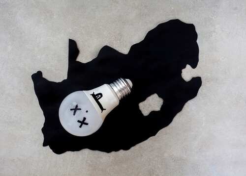 A light bulb with a face illustration placed on a black silhouette of South Africa