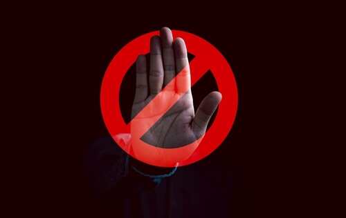 A hand raised in a stop gesture over a prohibition symbol