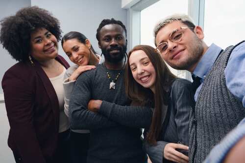 shutterstock_2478699791.jpg A diverse group of five people smiling together in an office setting