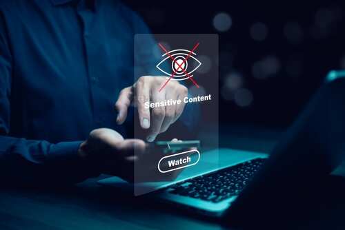 shutterstock_2531036903.jpg A person interacting with a digital screen displaying a sensitive content warning