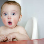 Trump’s Surprise Move Sparks Outrage A surprised baby sitting in a high chair with wide eyes and an open mouth