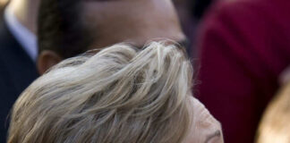 Person with short blonde hair, wearing gold earrings.