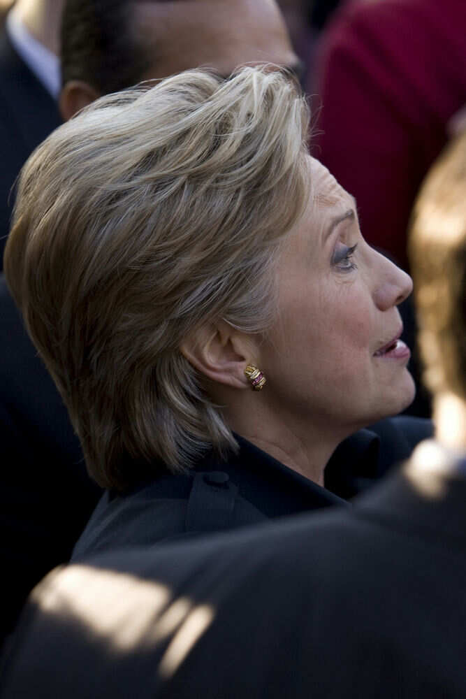 Person with short blonde hair, wearing gold earrings.