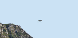 A UFO hovering above a mountain landscape