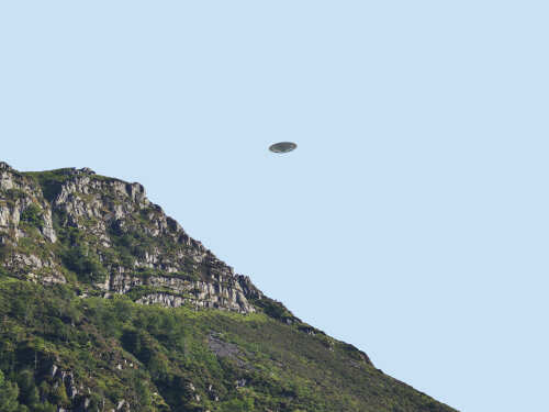 A UFO hovering above a mountain landscape