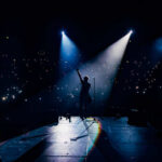 Pop Star’s Bold Attack on Cuba’s Regime Silhouette of a musician performing on stage with bright lights and an engaged audience