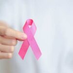 Person holding a pink ribbon symbolizing awareness