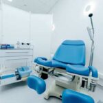 Predator Doctor Exposed—Sexual Misconduct Procedures A blue medical examination chair in a sterile healthcare room